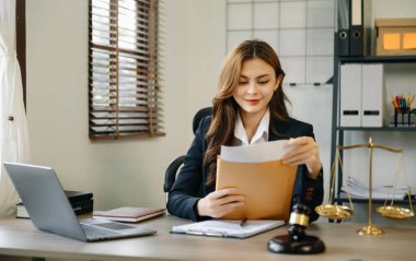 Ofisteki çekici genç avukat. Sözleşme kağıtları, dizüstü bilgisayarı ve pirinçleri olan iş kadını bir avukat, modern ofiste masanın üzerinde.. 