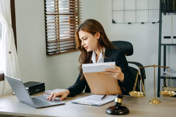 Attractive young lawyer in office Businesswoman and  contract papers, laptop and  brass scale on  desk in modern office.