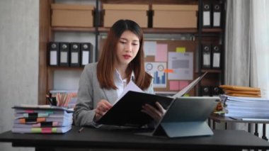 Beautiful Asian businesswoman with folder and tablet at the office