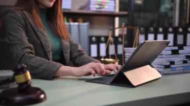 justice and law concept.female judge in a courtroom the gavel, working with digital tablet computer on wood table