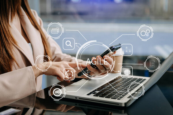 Agile development methodology concept. Businesswoman using laptop computer and phone with virtual screen Agile icon on modern office digital technology concept