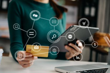 Woman using credit card and tablet pc for mobile payments online shopping,omni channel,sitting on table,virtual icons graphics interface screen