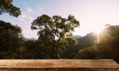 Empty top of wooden shelf on sky mountain and  trees front view background. For product display blur background image, for product display montage. in sunset