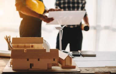 Engineer desk with object paper and tablet with blurry engineer teamwork hardworking to consults about their building project. in sunlight
