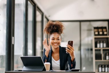 businesswoman  attending video conference and holding  smartphone  in modern office