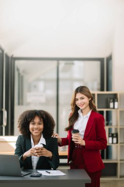 Two businesswomen working together with laptop  in modern office with coffee 