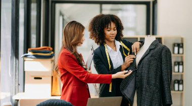 Diverse female fashion designers at work with tailor centimeters on neck . independent creative design business.