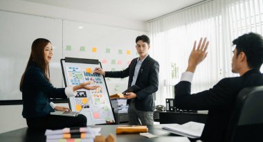 The boss stands near the board with graphs, demonstrates statistics, various personnel attending the training, introduces the new products of the company, in modern office