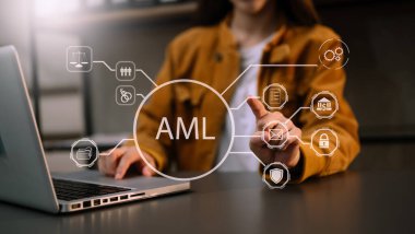 AML Para Aklamayla Mücadele Bankası İş Konsepti. İş kadını sanal ekranda AML para aklama ikonu içeren laptop ve tablet kullanıyor. Ofiste.