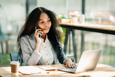 Businesswoman Talking on the phone and using a laptop at modern office