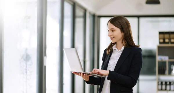 Confident business expert ,attractive smiling young woman holding laptop in office