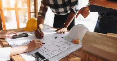 Mimari projeyle çalışan iş arkadaşları ofisdeki inşaat sahasında verileri tartışıyor