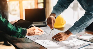 İş adamları ve Yaratıcı Mimarlar, sabah vakti karanlık çatı katındaki büyük çizimlere ya da kafeye bakıyorlar.