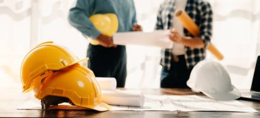 Engineer desk with object paper and  blurry engineer teamwork hardworking to consults about their building project. in office