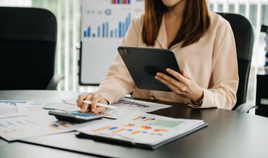 Kendine güvenen iş kadını, modern ofisindeki iş yerinde tablet üzerinde çalışıyor.