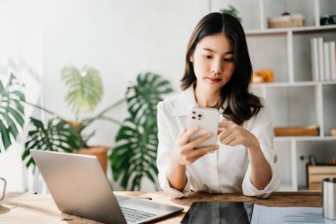  Çalışan kadın konsepti, video konferansına katılan Asyalı kadın yönetici ve ev ofisinde akıllı telefon ve bir fincan kahve.