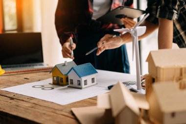 Modern ofisteki inşaat sahasında mimari projeyle veri çalışması ve tableti tartışan iki meslektaş