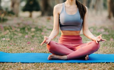 Bahçede yoga yapan genç bir kadının portresi. Kadın mutluluğu. Parkın arka planı bulanık.