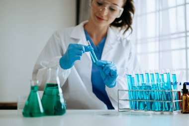 Kadın biyoteknoloji uzmanı bir laboratuarda yeni kimyasal maddeler test ediyor..