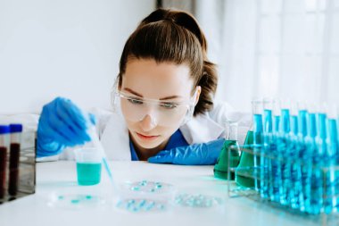 Kadın araştırmacı kimya laboratuvarında bir deney yürütüyor.