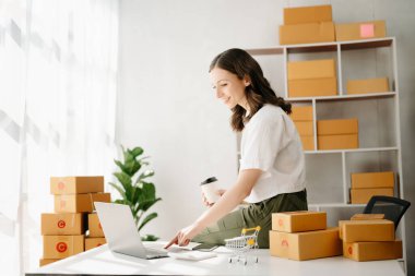 Başlangıçta küçük işletme KOBİ 'si, tablet bilgisayar kullanan girişimci kadın ürün kutularını hazırlamak için online alışveriş siparişlerini alır ve kontrol eder. ev ofisinde.