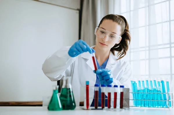 Kadın biyoteknoloji uzmanı bir laboratuarda yeni kimyasal maddeler test ediyor..