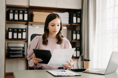 Ofisteki masada dizüstü bilgisayarı ve tableti olan güzel bir iş kadını.