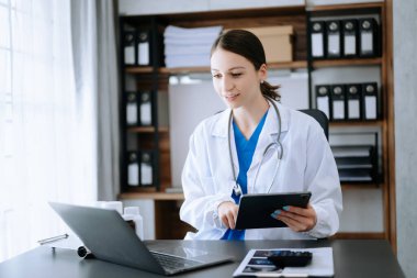 Tıbbi teknoloji konsepti. Modern ofiste bilgisayar, tablet bilgisayar ve steteskopla çalışan bir doktor.