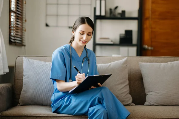 smiling doctor or consultant sitting on sofa with clipboard