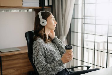 Gülümseyen kız evde dinleniyor, kulaklıkla müzik çalıyor.. 