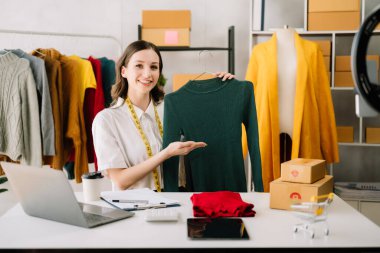  Terzi kadın terzi atölyesinde giysiler üzerinde çalışıyor. güzel genç bayan moda tasarımcısı gülümsemesi ve ofisteki başarıdan sonra