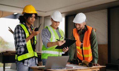 Müteahhit ve mimar plan, tablet, dizüstü bilgisayar ve büyük bir proje üzerinde çalışmaktan bahsediyorlar. İnşaat sürecinde bina içi