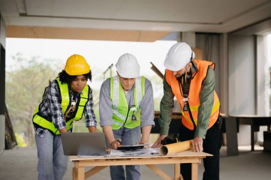 Mimar beyaz adam inşaat alanında meslektaşlarıyla karışık ırk üzerinde çalışıyor. Büyük projede mimarlık mühendisliği. İnşaat sürecinde bina içi.