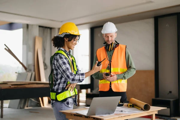 stock image Contractor and architect looking at plan,laptop and talking about working on big project. Building in construction process interior