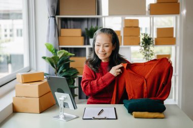 Moda blogcusu kavramı, üst düzey Asyalı kadın video yayınında kıyafet satıyor. Küçük işletme KOBİ 'si başlat, tablet alımı ve denetimi merkez ofiste kullan