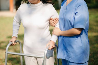 Asyalı, yaşlı, yaşlı, yaşlı bir kadın ve dikkatli bir bakıcı. Huzurevi hastane bahçesi konsepti.