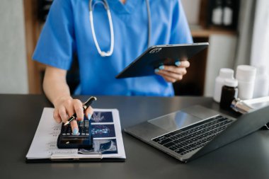 Akıllı doktor hastane masrafları için hesap makinesi ve tablet kullanmış. 