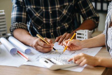 Two colleagues discussing data working  on architectural project at construction site at desk in modern office