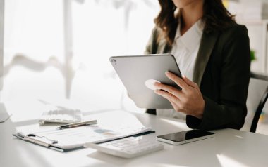 Kendine güvenen iş kadını, modern ofisindeki iş yerinde tablet üzerinde çalışıyor.