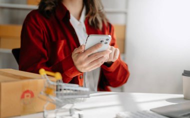 Elinde akıllı telefon tutan genç bir kadın ofiste online alışveriş kavramı olarak ödeme başarısını ve kredi kartını gösteriyor.