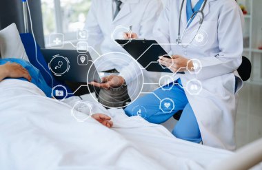 İki doktor hastanede salin solüsyonu alan bir hastayla konuşuyor. 