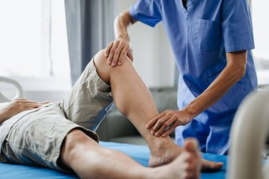 Klinikteki yatakta hastayla birlikte çalışan fizyoterapistin kapağını kapat.