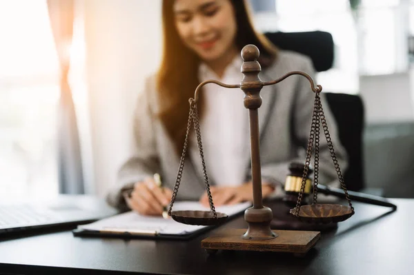 Female lawyer in the office with brass scale on wooden table. justice and law concept