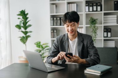 Genç yakışıklı Asyalı adam ve laptop evden çalışıyor.