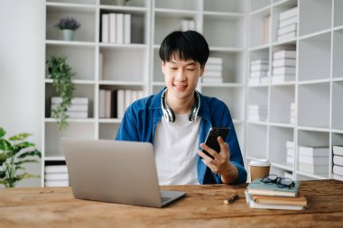 Genç yakışıklı Asyalı adam ve laptop evden çalışıyor.