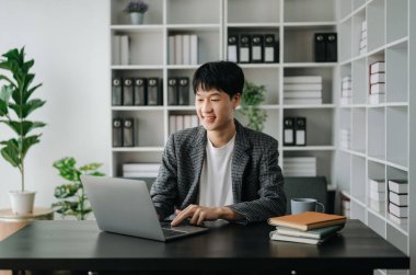 Genç işadamı ofiste dizüstü bilgisayarla çalışıyor.