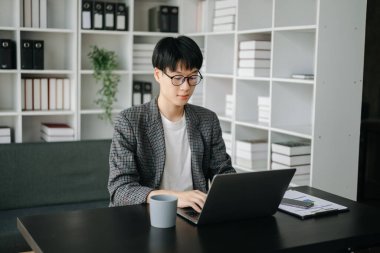 Genç iş adamı yönetici dizüstü bilgisayara bakıyor online webinar eğitimi izliyor ya da modern ofiste pazar araştırması yaparak sanal toplantı videosu konferansı yapıyor.