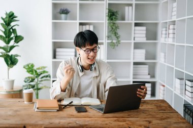 Kütüphanedeki bir kitaptan notlar alan erkek öğrenci, üniversite kütüphanesinde ödev yapan Asyalı genç adam.