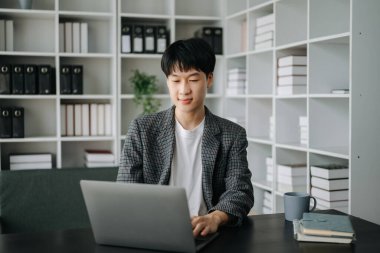 Genç işadamı ofiste dizüstü bilgisayarla çalışıyor.