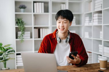 Genç yakışıklı Asyalı adam ve laptop evden çalışıyor.